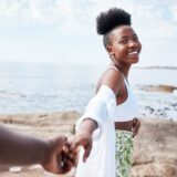 Beach, travel and holiday, black couple holding hands while on a walking at the ocean. Nature, love