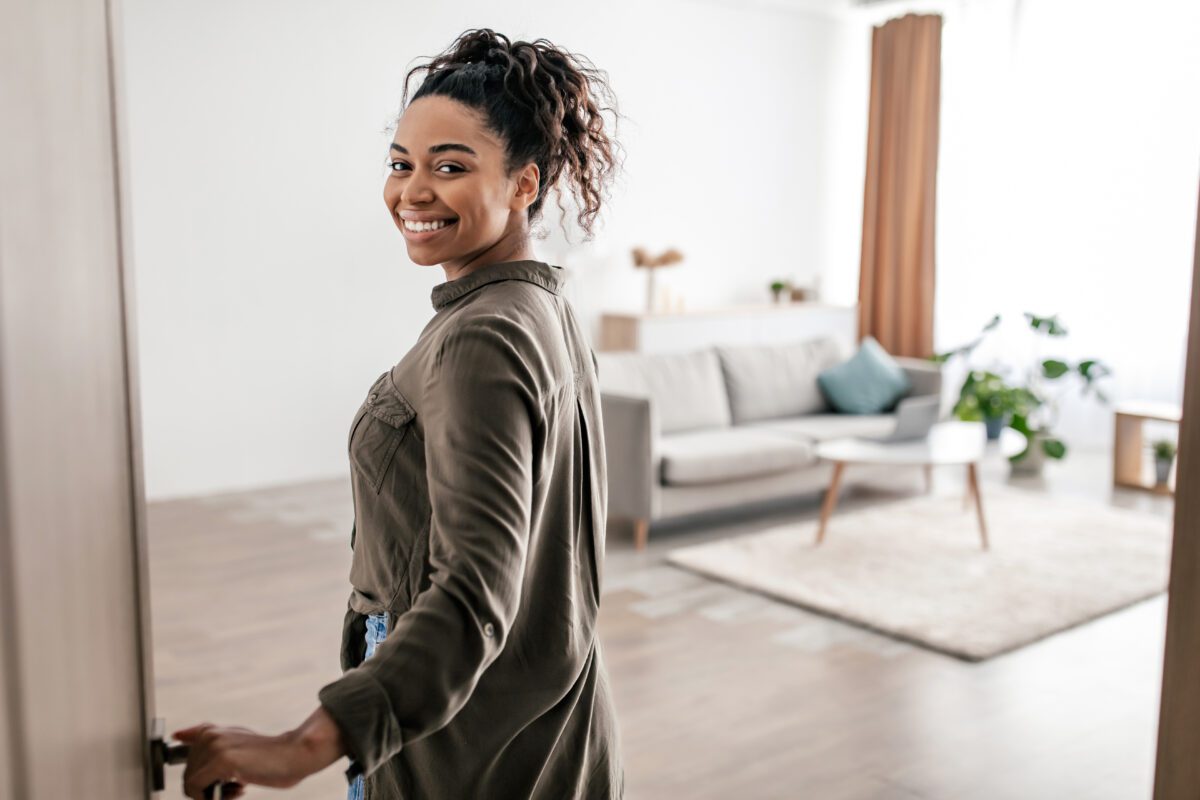 Cheerful Black Female Opening Entry Door Entering Apartment